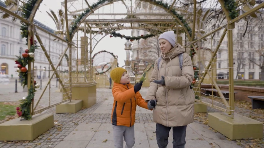 A person and child holding hands while walking in the city.