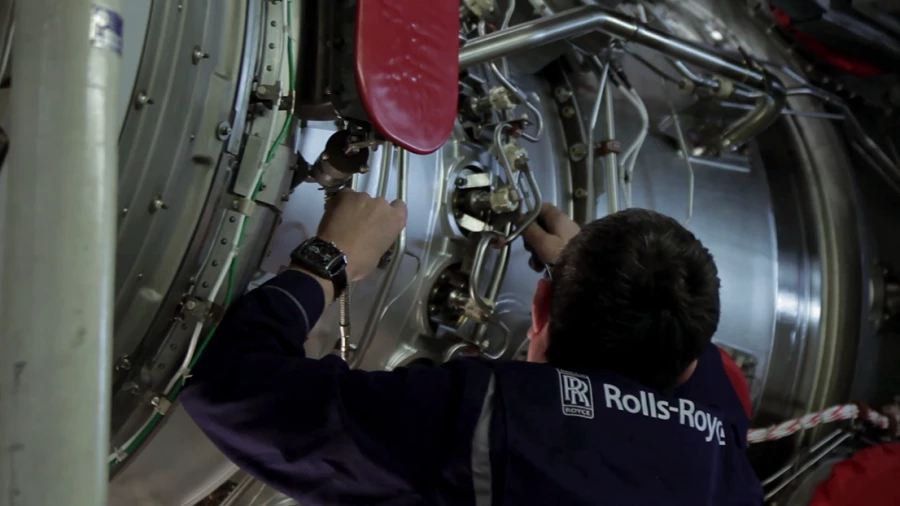 A Rolls Royce Engines mechanic working on an airplane engine.